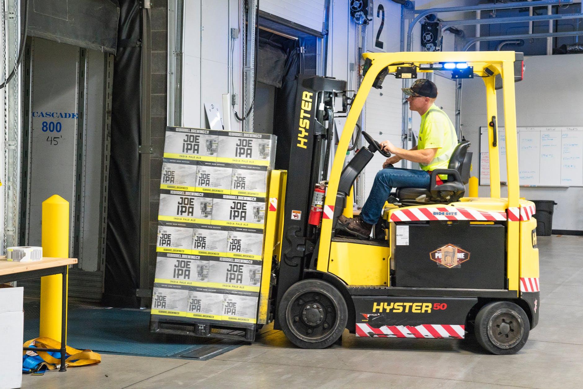 man riding a yellow forklift with boxes